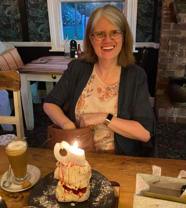 Ann Kinnish smiling with a birthday cake and a latte 