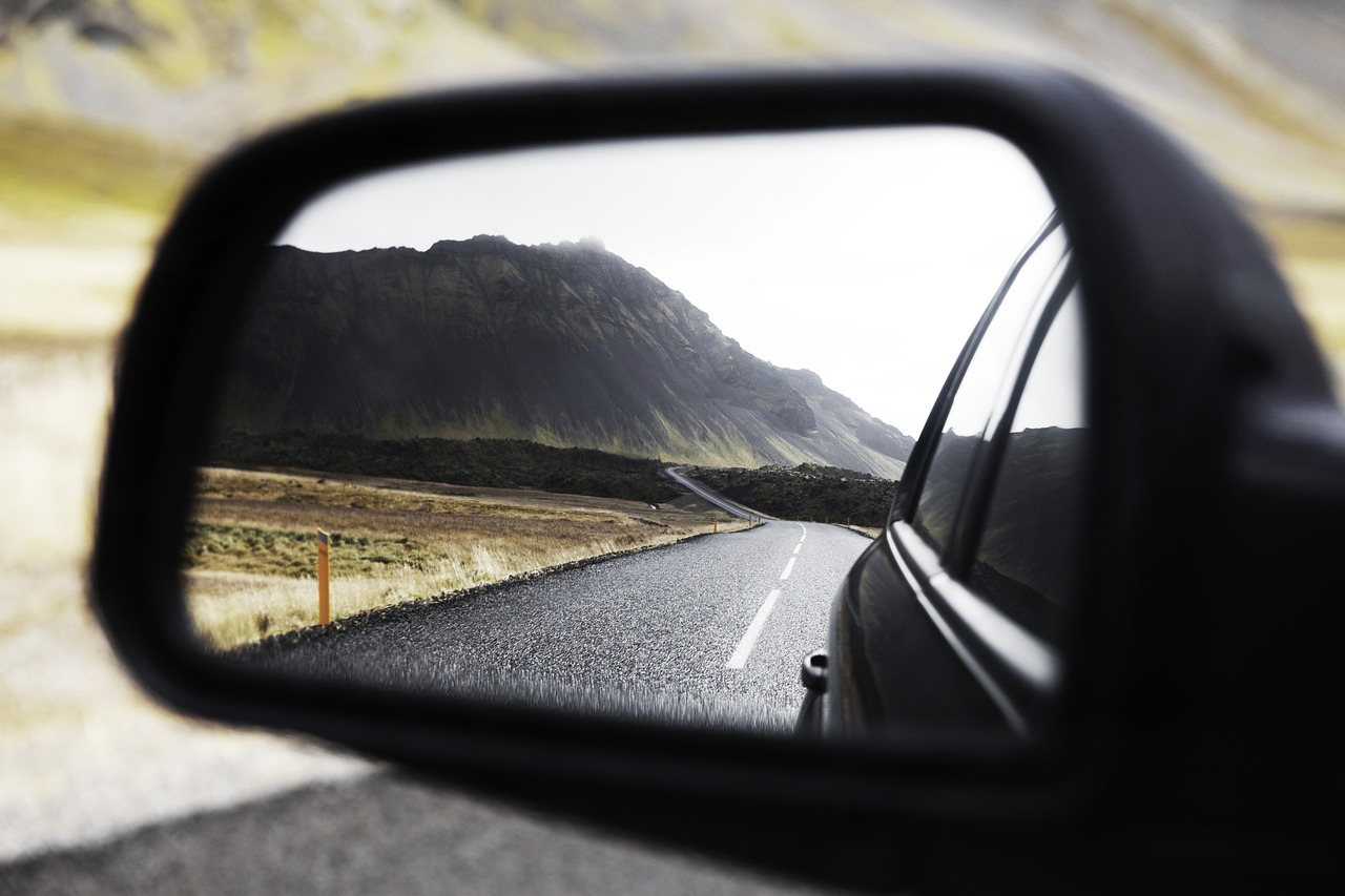 From inside a car, the photo is looking at the wingmirror, the road in the mirror is clear and in focus.