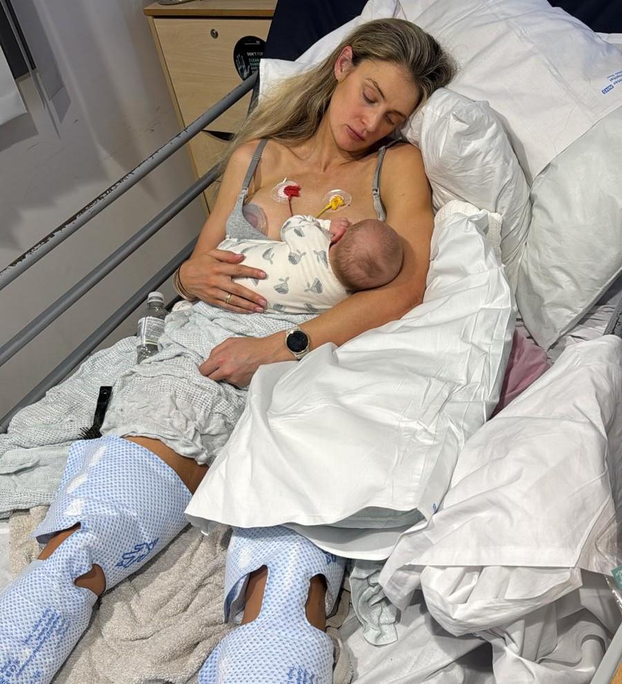 A young woman breastfeeds her infant while in a hospital bed