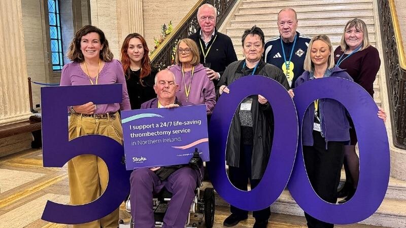 A group of campaigners in Northern Ireland supporting a 24/7 thrombectomy service hold up a large number '500' at Stormont