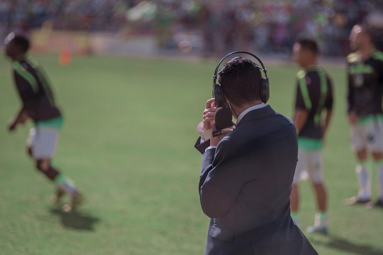 Image of football commentator on pitch
