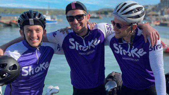 Three cyclists pose wearing Stroke Association shirts after a sports event