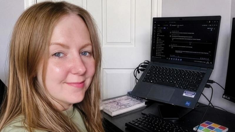 Stroke Support Helpline Officer, Kim, sits in front of her computer, smiling, ready to take a call. 