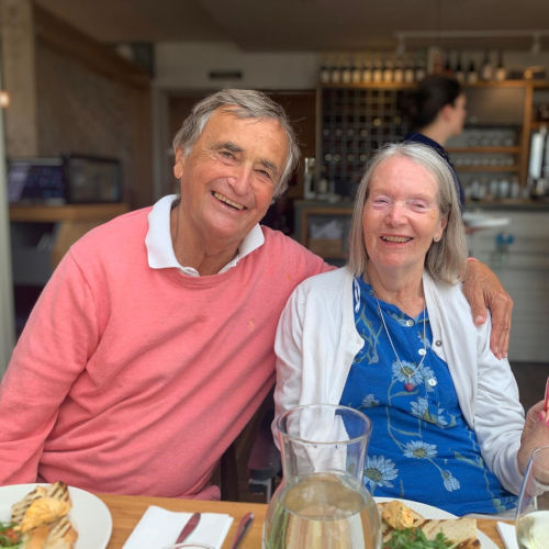A man sat with his arm around a woman.