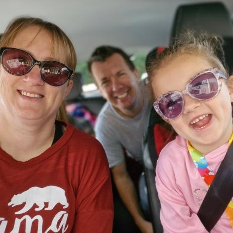 Emily, a childhood stroke survivor, smiling in the car with her parents