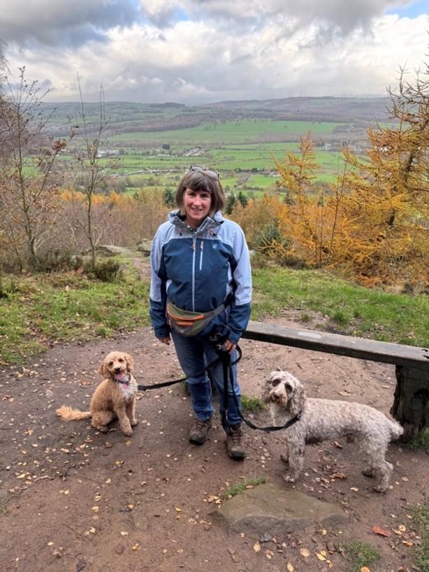 A photo of stroke survivor Linda Shields, with her 2 dogs, outside with a landscape view behind her