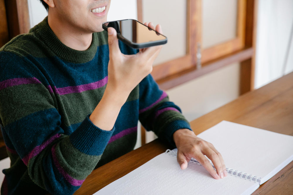 person at desk with book and talking on phone