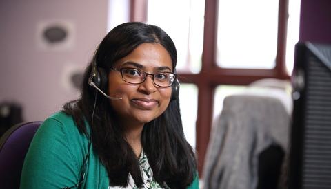 Stroke association helpline worker wearing headset smiling