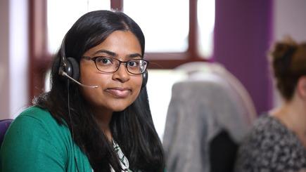 Stroke association helpline worker wearing headset smiling