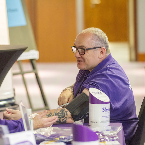 Man wearing purple having his blood pressure taken