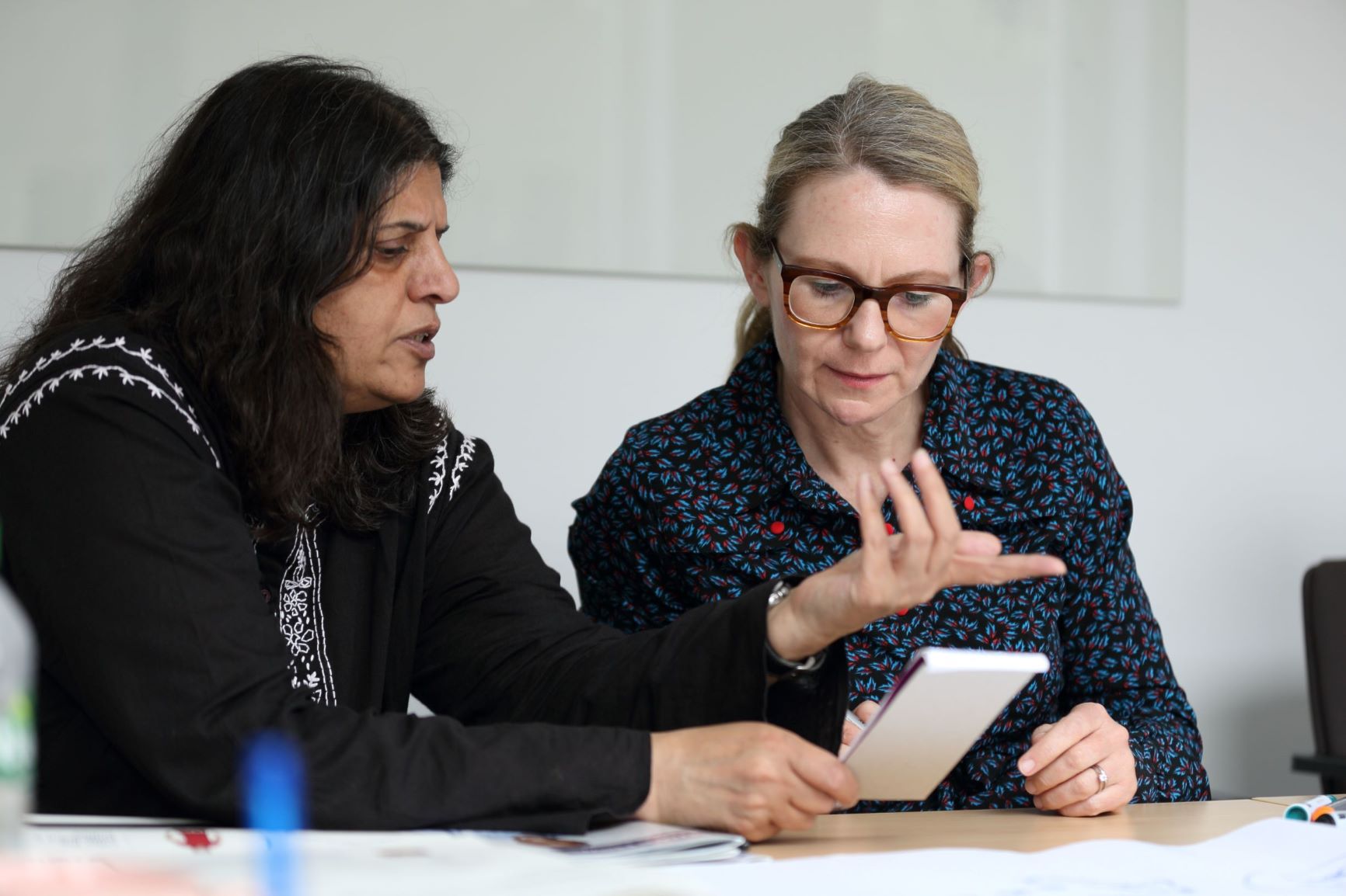Two women discussing something written on a piece of paper