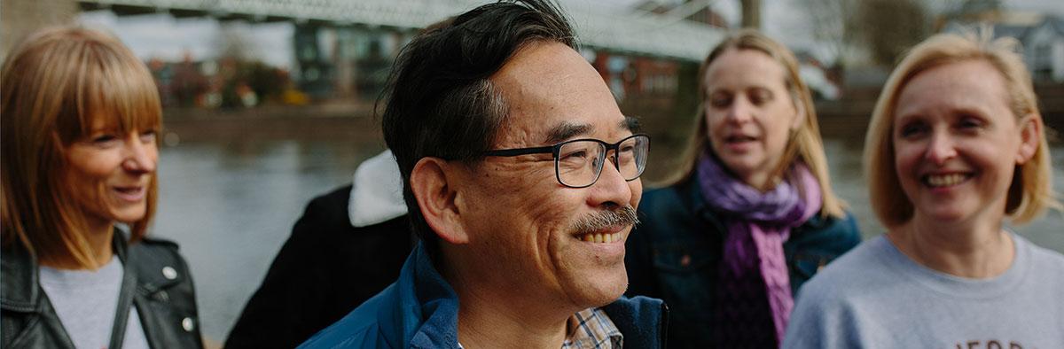A man smiling among a group of people that are also smiling.