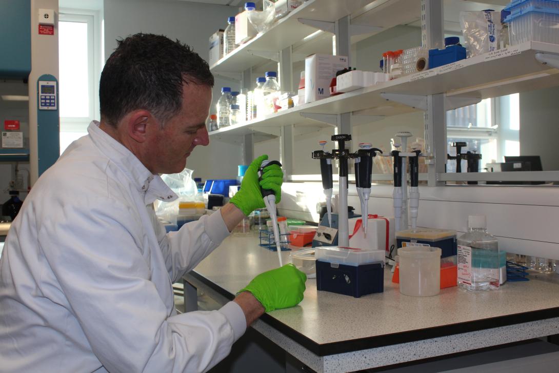 Dr. Jones dressed in a white lab coat sat at a lab table using scientific research equipment
