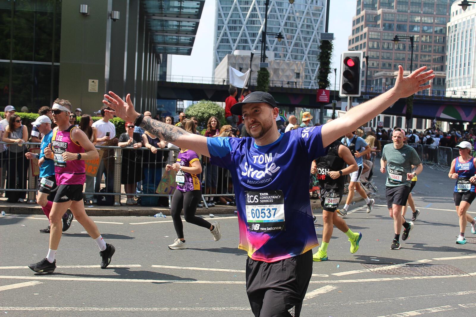A photo of someone in the London Marathon in a stroke running top, with their arms outstretched