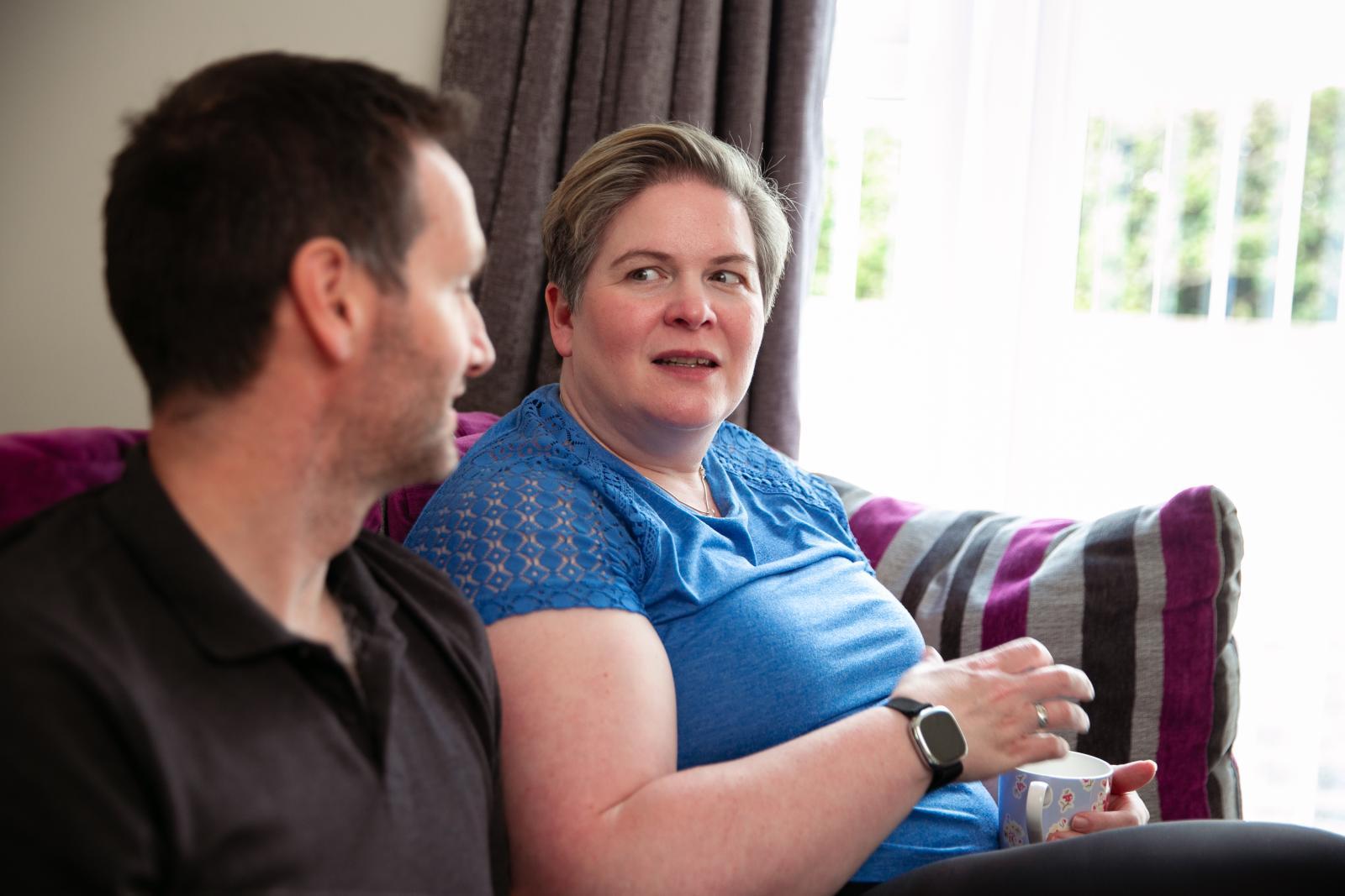 Man and woman sat on a sofa chatting.