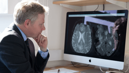 Man looking at brain scans on his computer screen
