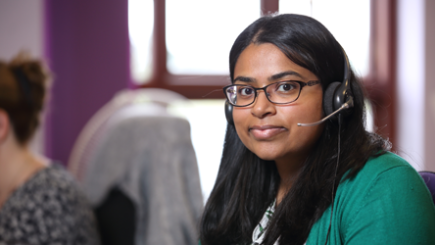 Stroke association helpline worker wearing headset smiling