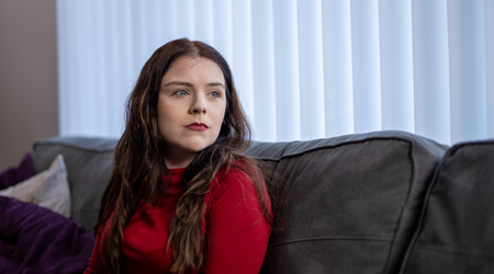 Photo of Grace sitting on a sofa, looking off camera