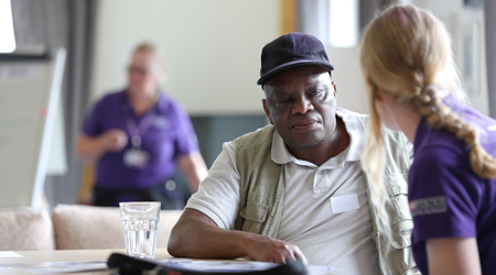 Photo of a stroke survivor in conservation with someone in a Stroke Association uniform