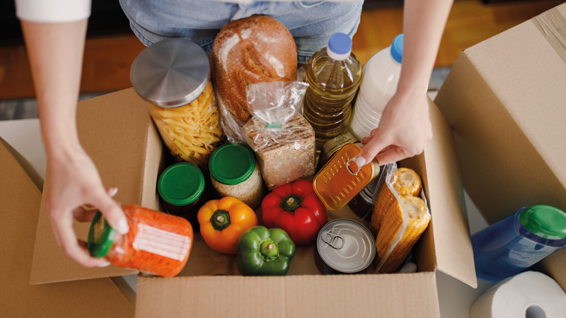 A person sorts through a box of groceries