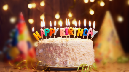 A cake with candles spelling out Happy Birthday