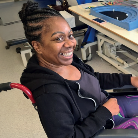 A photo of Sue McAlpine in a wheelchair, smiling at the camera